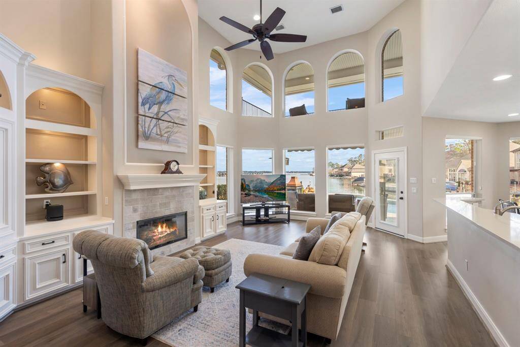 This stunning living room flooded with natural light and panoramic lake views. The soaring ceiling, stone fireplace, and custom built-ins exude elegance and warmth.