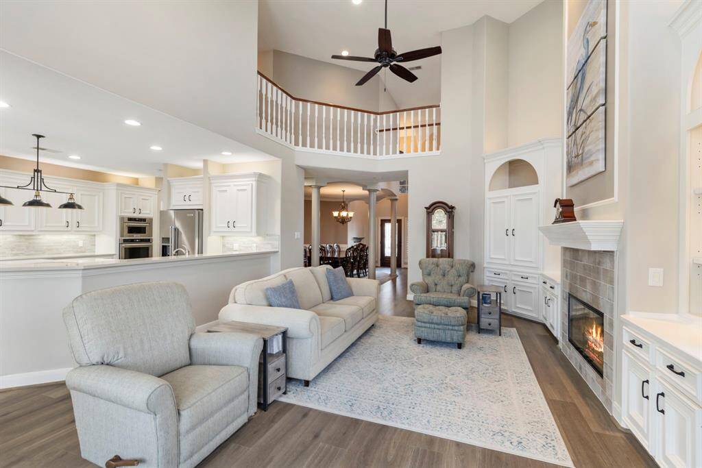 The open-concept design features a soaring ceiling and fireplace, perfect for gatherings or quiet evenings. A seamless flow into the modern kitchen makes entertaining a breeze.
