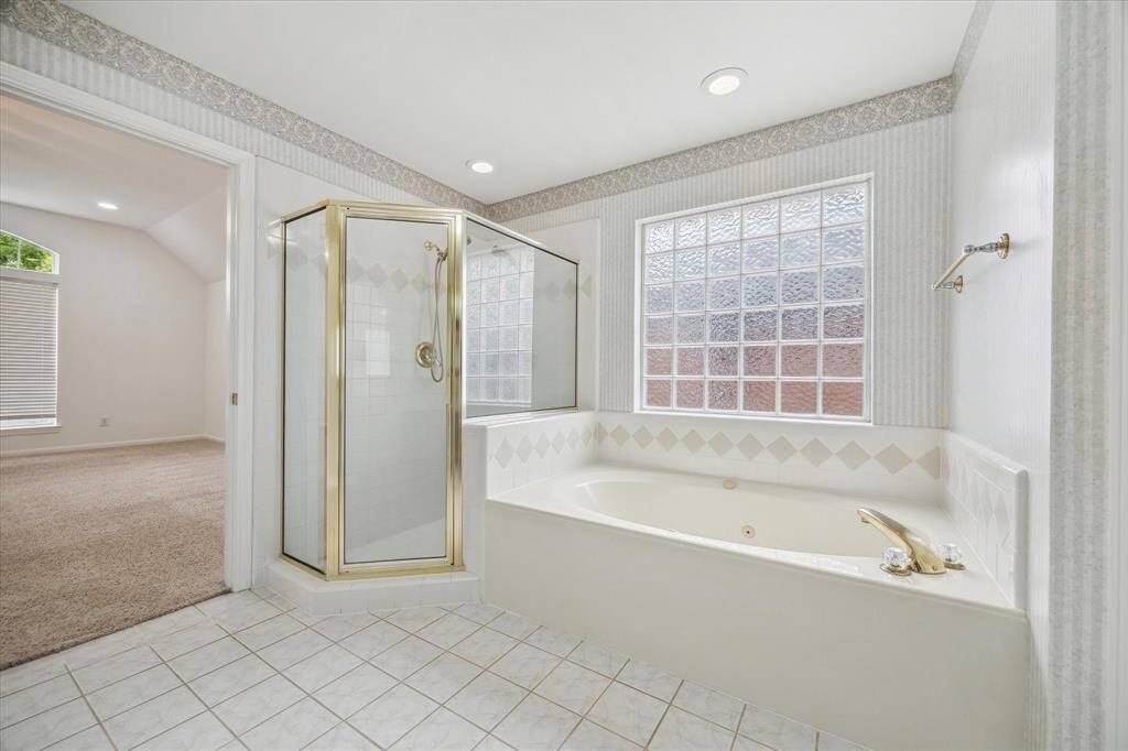 Another view of the primary bathroom showing the glass enclosed shower and separate soaking tub.