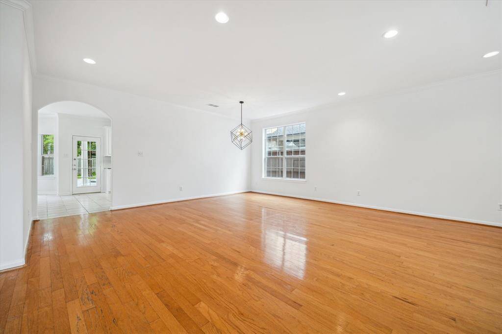 Spacious living and dining area with hardwood floors, white walls, and recessed lighting. It features a large window providing natural light, perfect for special entertaining!
