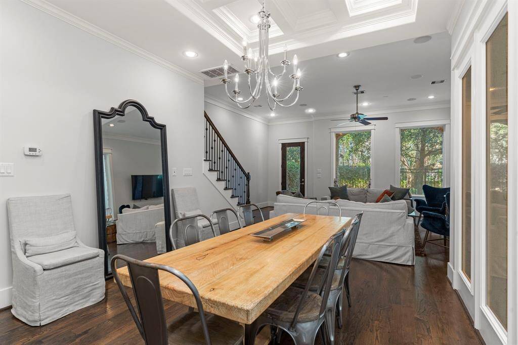 The home offers a seamless connection between the living and dining areas, highlighted by high ceilings, elegant crown molding, recessed lighting, stunning fixtures, and expansive windows that invite the outdoors in. The exquisite coffered ceiling adds a special touch we absolutely love!