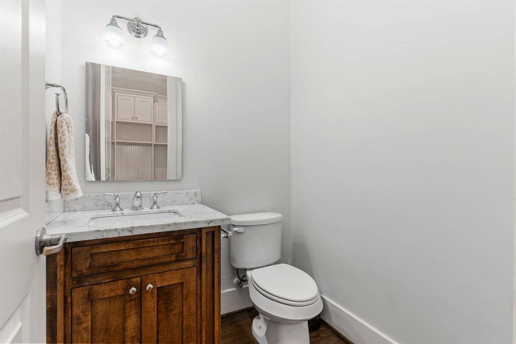 The first-floor living spaces are complemented by a convenient half bath, featuring a stone countertop, wood cabinetry, and chrome finishes.