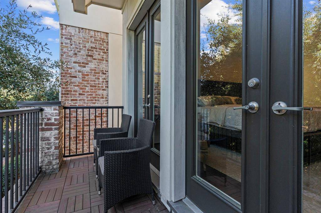 The front balcony off the primary suite provides a perfect spot for outdoor relaxation, offering views of the serene treetops, beautiful street, and peaceful surroundings.