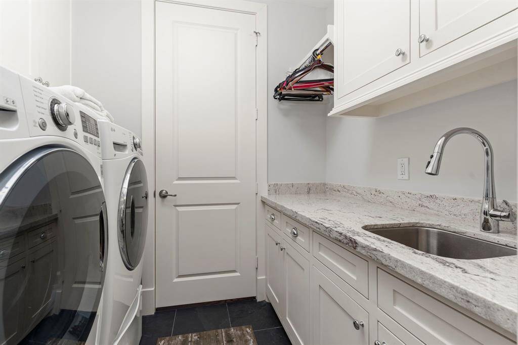The impressive walk-in closets in the primary bedroom lead directly into the conveniently located, expansive laundry room, complete with a sink, ample cabinet space, and excellent storage solutions.