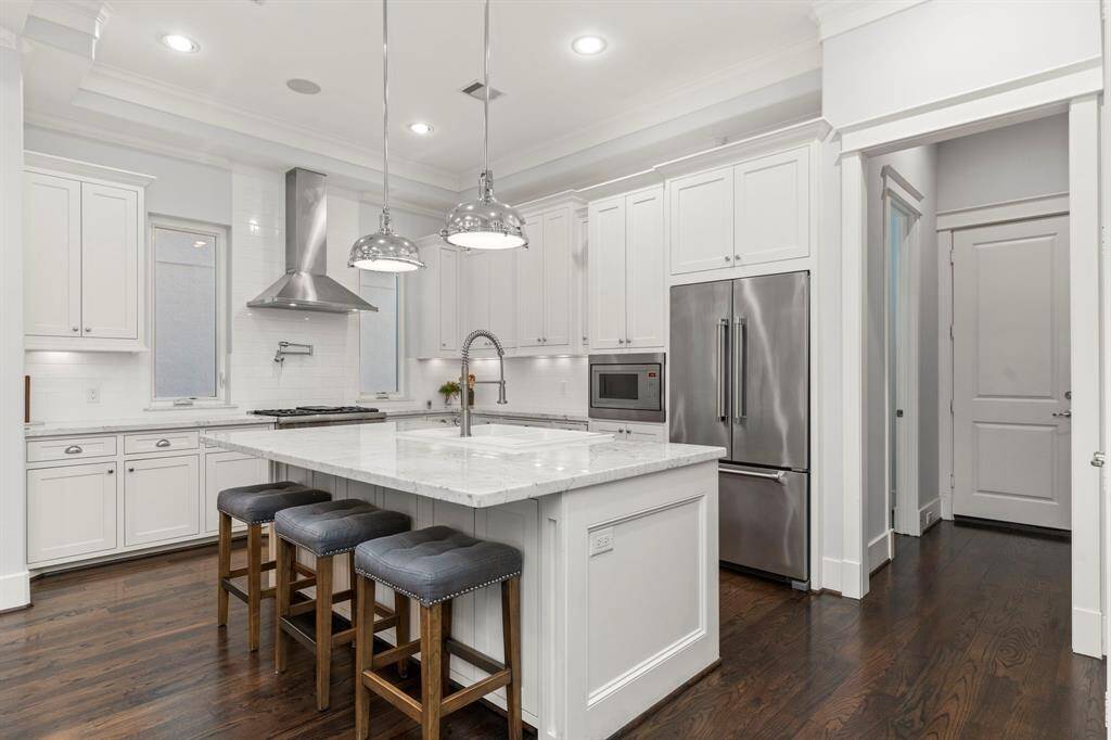 The central island/breakfast bar is beautifully accented by two sleek and modern pendant lights.