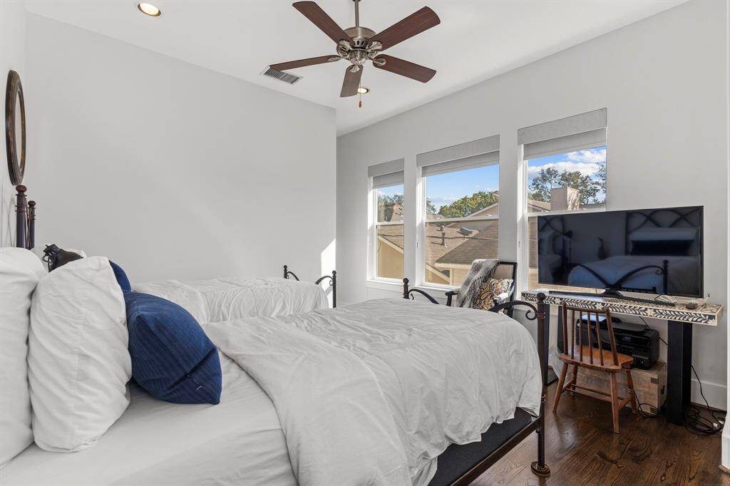 The third bedroom features hardwood flooring, recessed lighting, a ceiling fan, a private ensuite bathroom, and large windows.