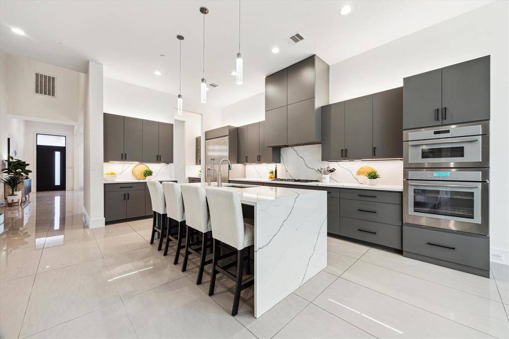 [KITCHEN] A culinary masterpiece designed for both function and style, this chef’s kitchen showcases top-of-the-line Thermador appliances, sleek custom cabinetry, and a striking waterfall island adorned with stunning quartz stone.