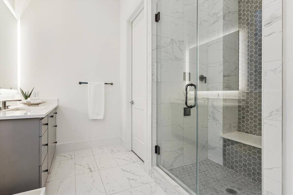 The in-law suite’s en-suite bath is both stylish and functional, featuring dual vanities with sleek finishes and a spacious walk-in shower with contemporary tilework.