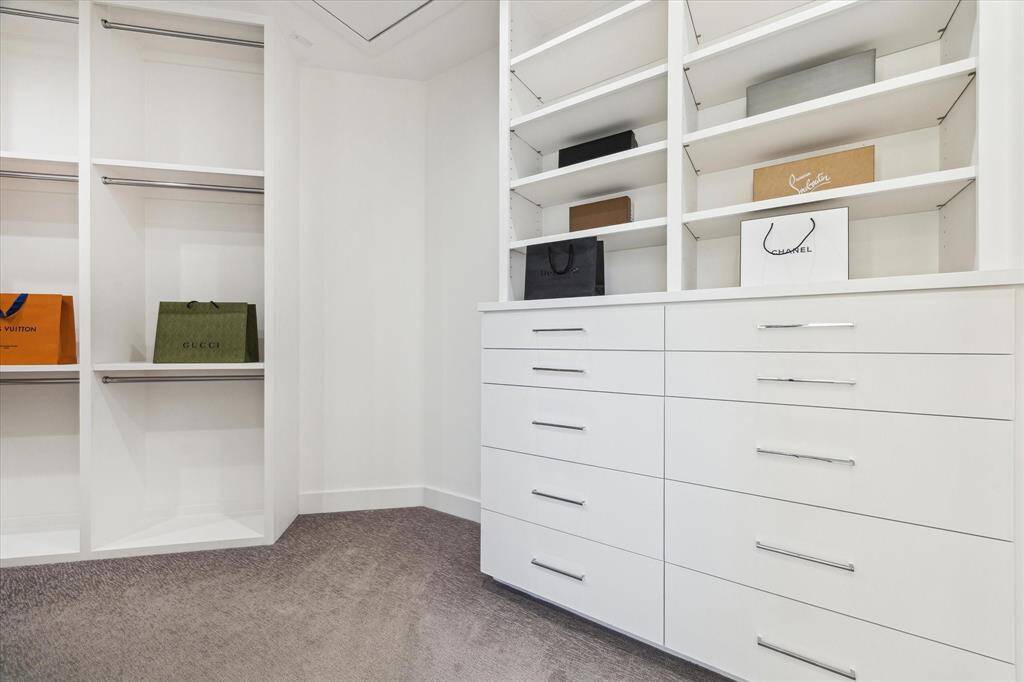 [PRIMARY CLOSET] The custom-fitted primary closet is a masterpiece of organization and style, offering a thoughtfully designed layout with sleek shelving, drawers, and ample hanging space.