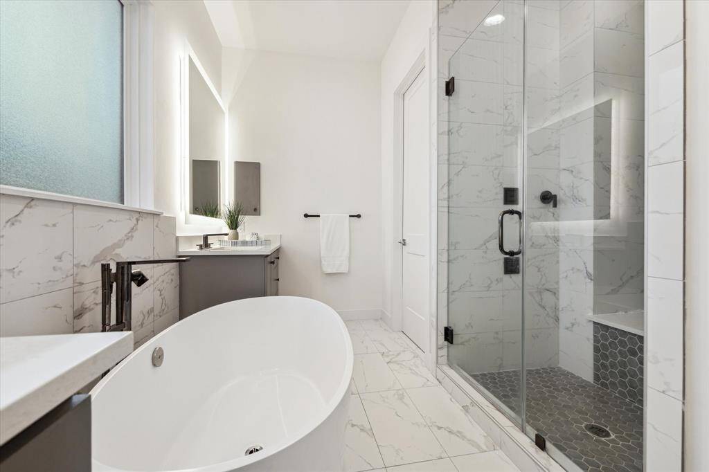 The freestanding tub invites relaxation, while the large walk-in shower, complete with a built-in seating bench, provides a serene retreat.