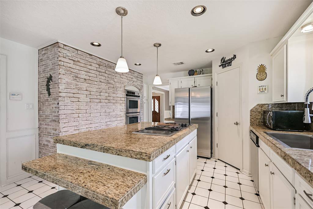 Center island with 7-burner electric cooktop. Stainless steel appliances + corner pantry.