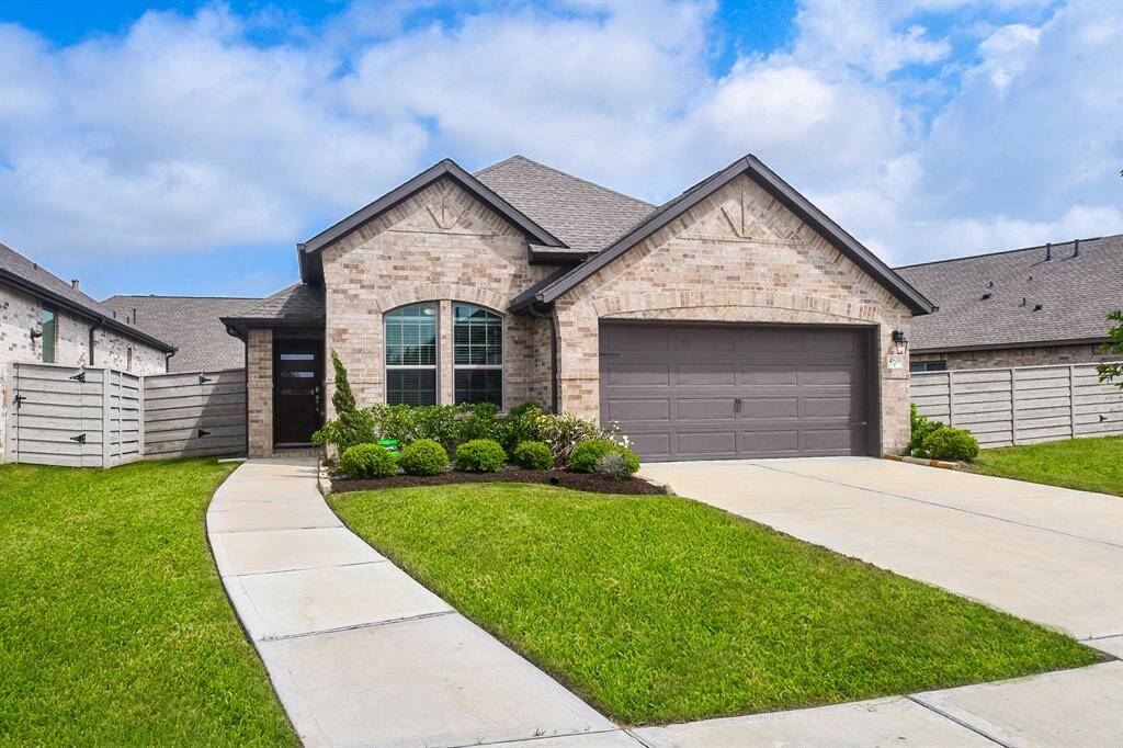 This charming single-story home features a brick exterior, a two-car garage, and a neatly landscaped front yard. The inviting walkway leads to a stylish entrance, enhancing curb appeal.