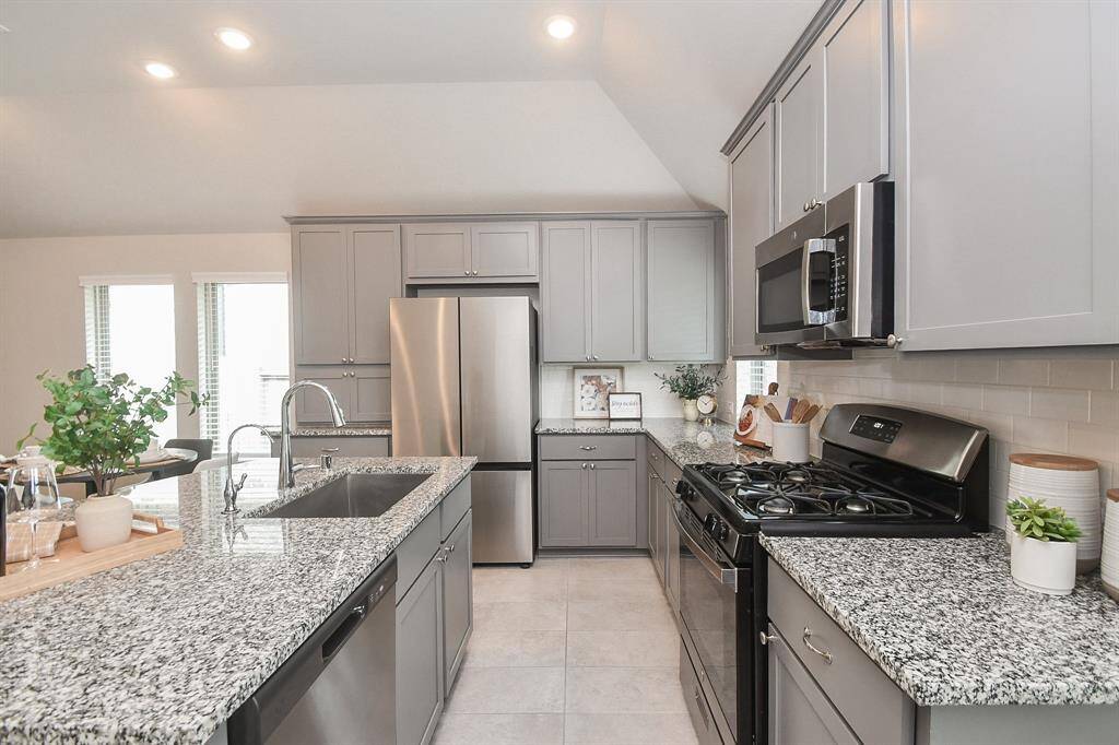 Modern kitchen with granite countertops, stainless steel appliances, and ample cabinet space. Bright and inviting with recessed lighting and neutral tones.
