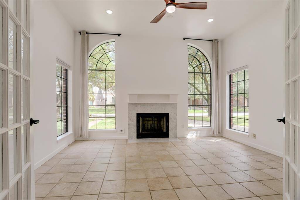 Living Room featuring a fireplace with marble surround, French doors and large window providing ample natural light.