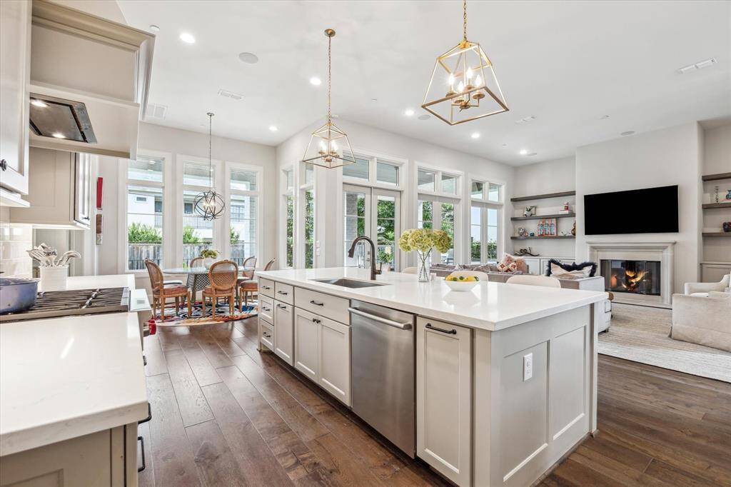 An additional view of the kitchen reveals its seamless integration with the breakfast area and family room, framed by walls of windows that flood the space with natural light. The expansive quartz island anchors the open layout, offering a perfect vantage point for entertaining or everyday living.