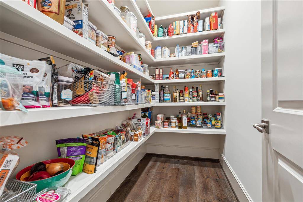 This spacious walk-in pantry is thoughtfully designed with deep, wraparound shelving that offers abundant storage and effortless organization for every culinary essential.