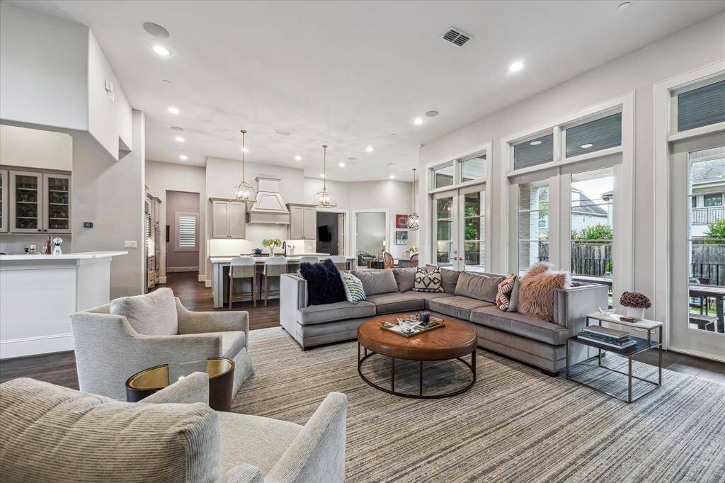Bathed in natural light from a wall of oversized windows, this elegant family room offers an inviting atmosphere with soaring ceilings, wide-plank hardwood floors, and seamless flow into the designer kitchen. The open-concept layout is perfect for both relaxed living and sophisticated entertaining, framed by refined finishes and soft, contemporary tones.