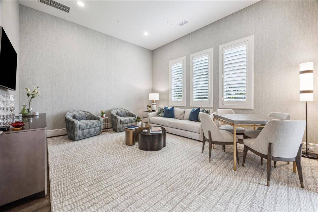This beautifully appointed flex space offers a serene, sophisticated atmosphere with soft-toned wallpaper, tailored window shutters, and plush textured carpeting. Whether used as a secondary lounge, media retreat, or game room, the space is thoughtfully designed with ample room for both relaxation and entertaining, effortlessly blending comfort with refined style.