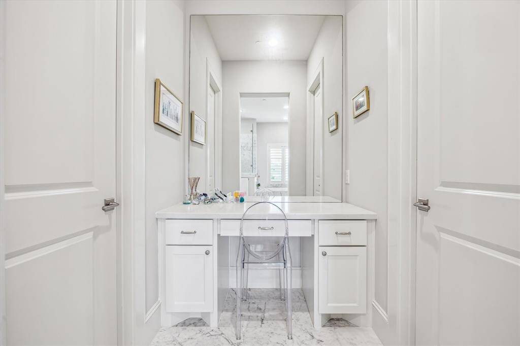An added touch of luxury, this built-in vanity area just off the primary bath offers a dedicated space for daily rituals, complete with marble surfaces, ample storage, and an oversized mirror that enhances both style and function.