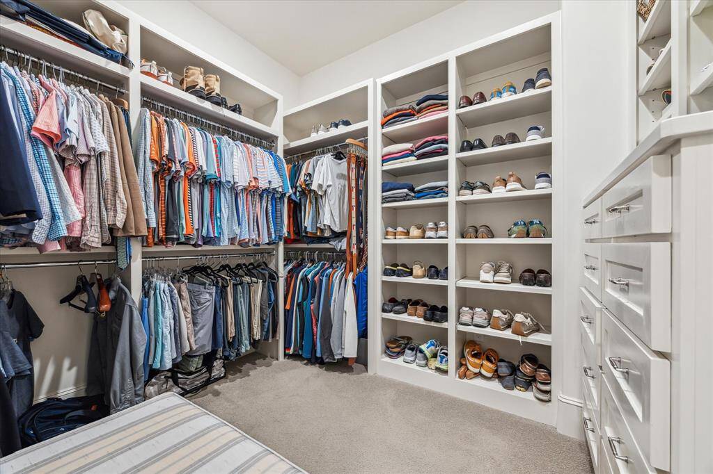 The expansive primary closet is expertly designed with custom built-ins, abundant shelving, and generous hanging space to keep wardrobes beautifully organized and effortlessly accessible.