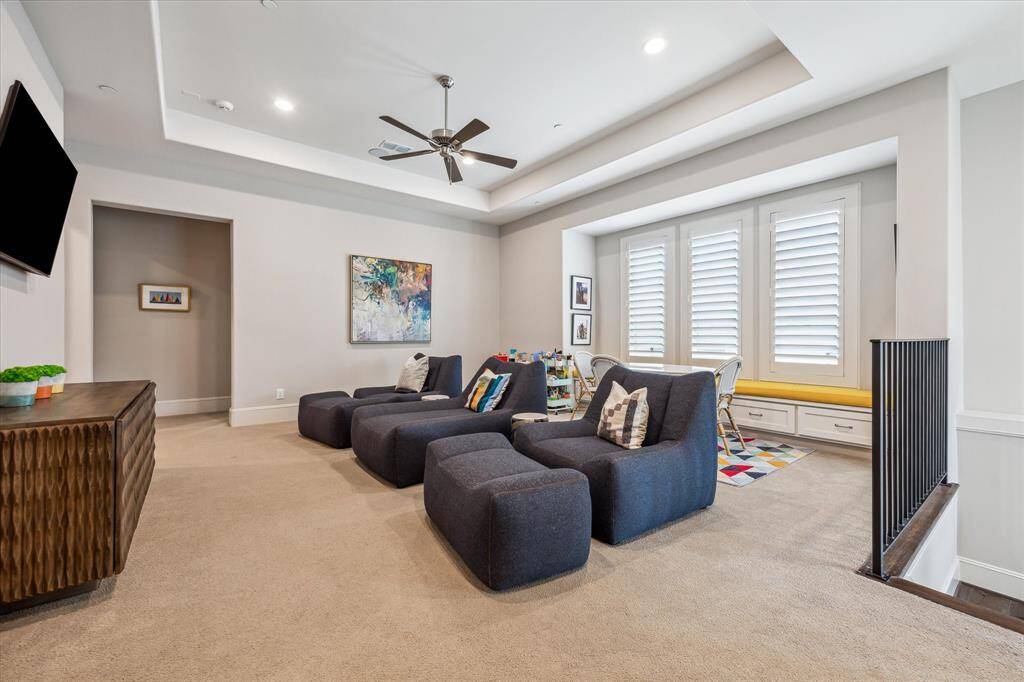 The second-floor game room is a spacious and versatile retreat, featuring a tray ceiling, built-in window seat with storage, and ample room for lounging, play, or study. Bathed in natural light from plantation-shuttered windows, this flexible space adapts effortlessly to entertainment or relaxation.