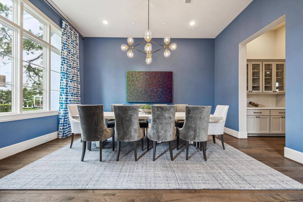 The formal dining room makes a bold yet sophisticated statement with its rich blue walls, contemporary chandelier, and striking floor-to-ceiling windows that flood the space with natural light. Perfect for elegant entertaining, this vibrant space is thoughtfully positioned next to a butler’s pantry for effortless hosting.