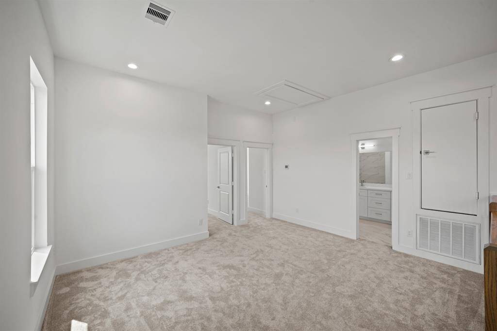 This is a bright, spacious room with fresh carpet and recessed lighting. It features a door leading to a bathroom with modern fixtures, adding convenience and style.