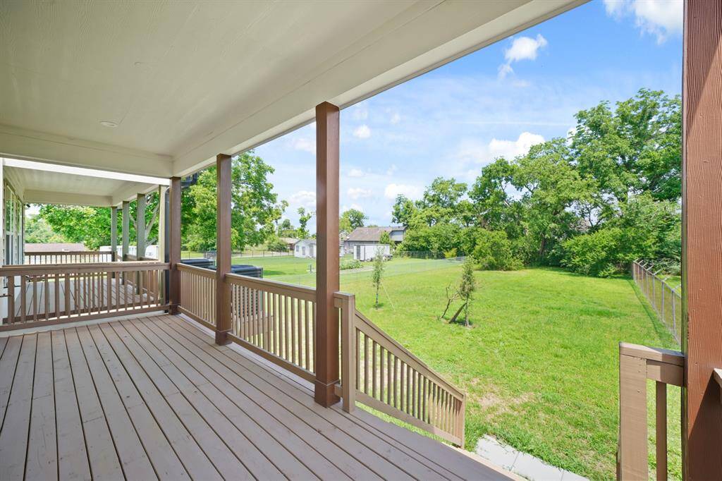 Spacious covered deck overlooking a large, lush backyard with mature trees, perfect for outdoor relaxation and entertainment.