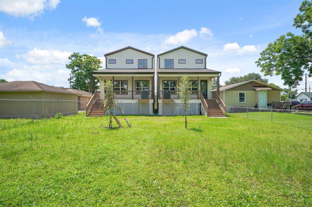 This photo shows a charming two-story home with a covered front porch and a spacious fenced yard, ideal for family gatherings. The property has a bright exterior and is flanked by trees, adding to its appeal.