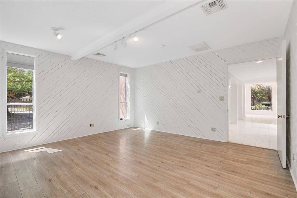 This is a bright, spacious room featuring vinyl flooring, white diagonal shiplap walls, recessed lighting, and multiple windows for ample natural light. This room adjoins with the guest suite. This room could be transformed into a media room or possible a 1st floor primary bedroom