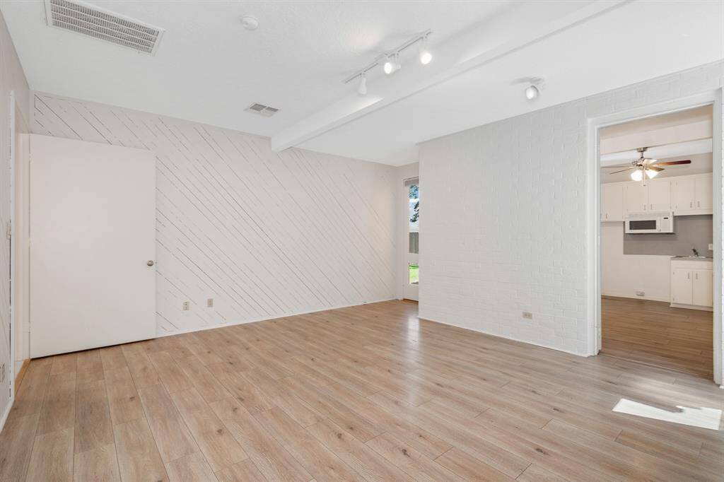 This is a bright, spacious room featuring vinyl flooring, white diagonal shiplap walls, recessed lighting, and multiple windows for ample natural light. This room adjoins with the guest suite. This room could be transformed into a media room or possible a 1st floor primary