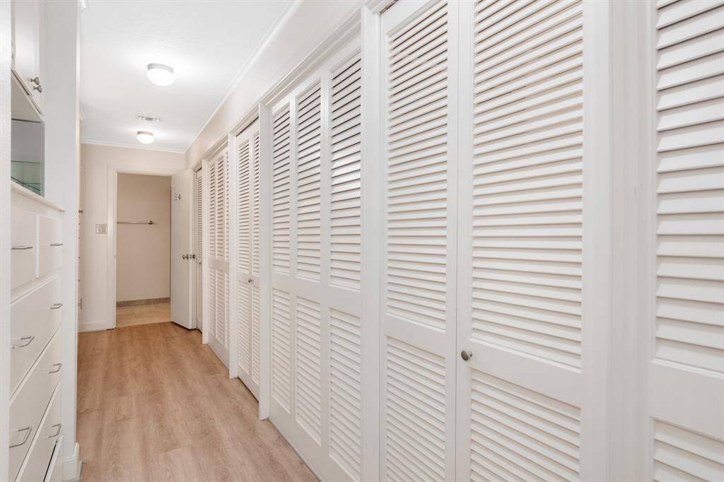 Walk in closets or storage, with a vinyl floor and built-in shelving to the left. A clean, practical space for organizing belongings in primary suite.