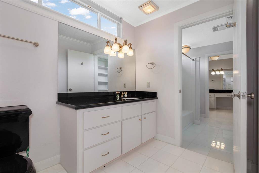 Bath with single vanity off bedroom #4. Featuring elegant gold fixtures and small horizontal windows to allow natural light.