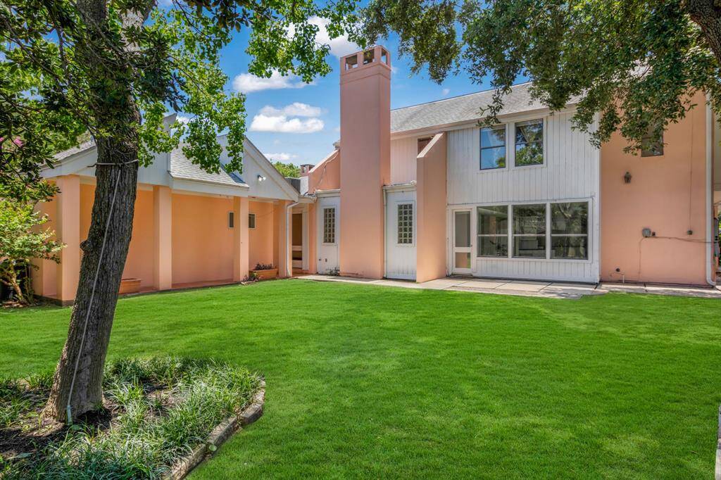 This is a modern two-story home with a peach- exterior and white accents, featuring large windows, and mature trees providing ample shade.