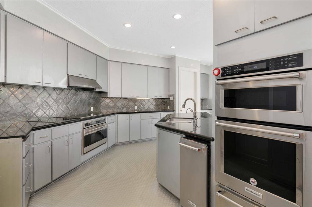 Modern kitchen featuring stainless steel appliances, ample cabinetry, and a sleek backsplash. The space is completed with a convenient double oven.