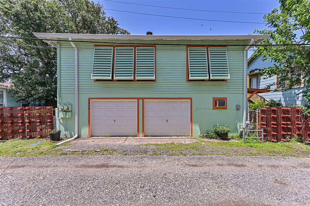 Charming two-story home with a mint-green exterior and orange trim. Features a double garage and unique shuttered windows. Surrounded by greenery, it offers a cozy and colorful appeal.