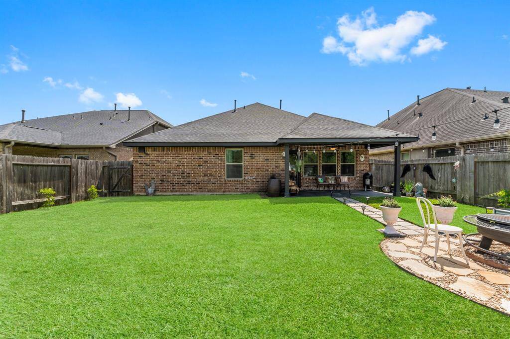 Spacious backyard with a well-maintained lawn, covered patio, and seating area. Perfect for outdoor entertaining and relaxation.