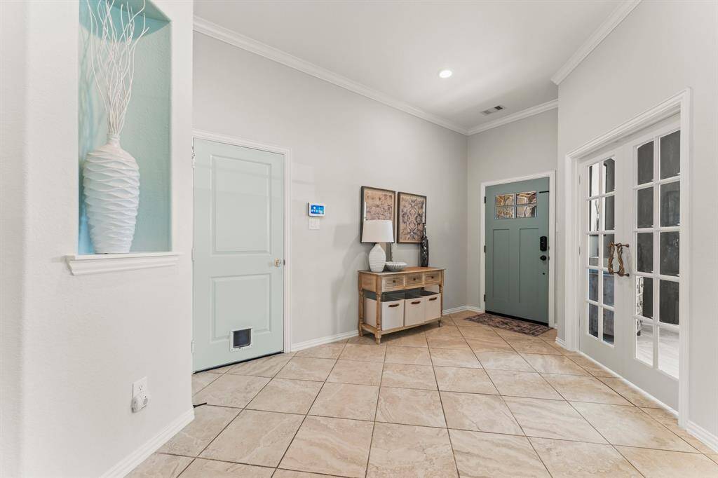 Spacious entryway with elegant French doors leading to a home office.