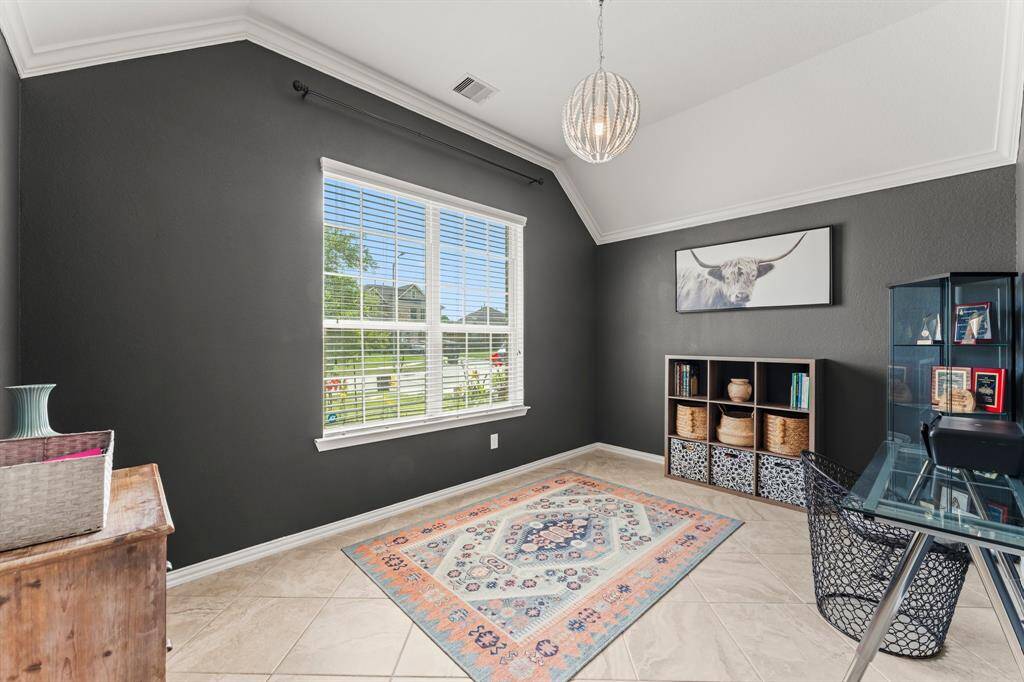 Elegant home office featuring French doors, crown molding, and tile flooring, with picturesque views of the front yard and cul-de-sac.