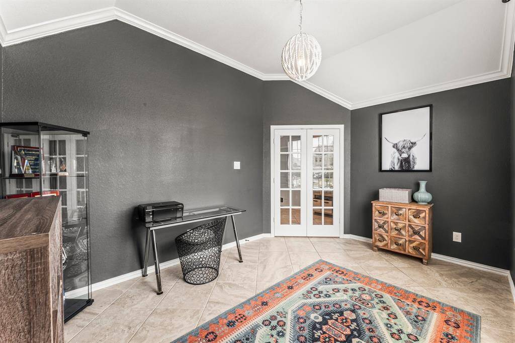 The front room can flex to meet your specific needs and features a high ceiling. It includes a stylish light fixture, French doors, and custom paint. The space is versatile, suitable for an office or cozy sitting area.