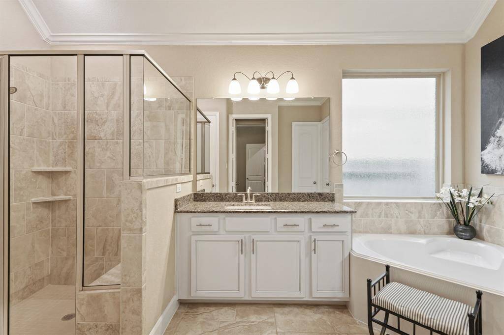 Welcome to your very own retreat! Relax after a long day in this wonderful primary bathroom with a soaking tub, glass enclosed shower, and modern fixtures.