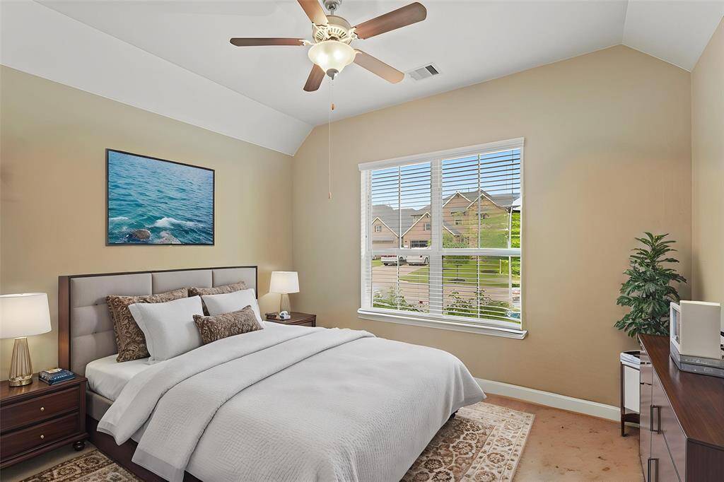 Virtually Staged: Secondary bedroom with carpet floors, a window with privacy blinds, and a tray ceiling with a ceiling fan.
