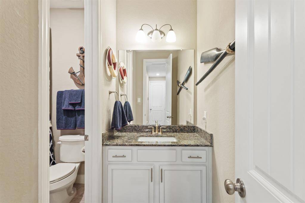 Secondary bathroom with granite countertops and backsplash.
