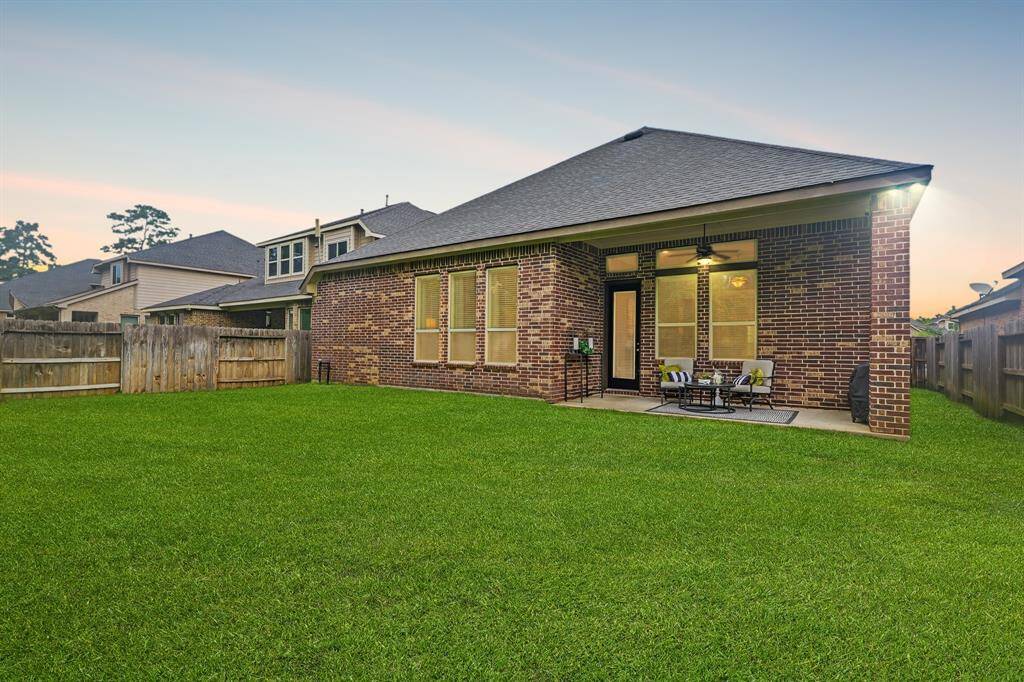 The covered patio with brick accent has a ceiling fan, and is perfect for outdoor seating and dining.