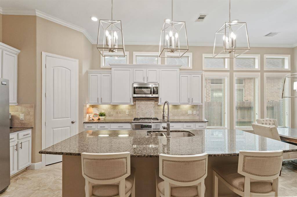 Host your next dinner party with confidence! This masterfully-equipped kitchen features an island with breakfast bar, an abundance of cabinetry and hardware, TONS of counter space, granite countertops, stainless-steel appliances, and a walk-in pantry.