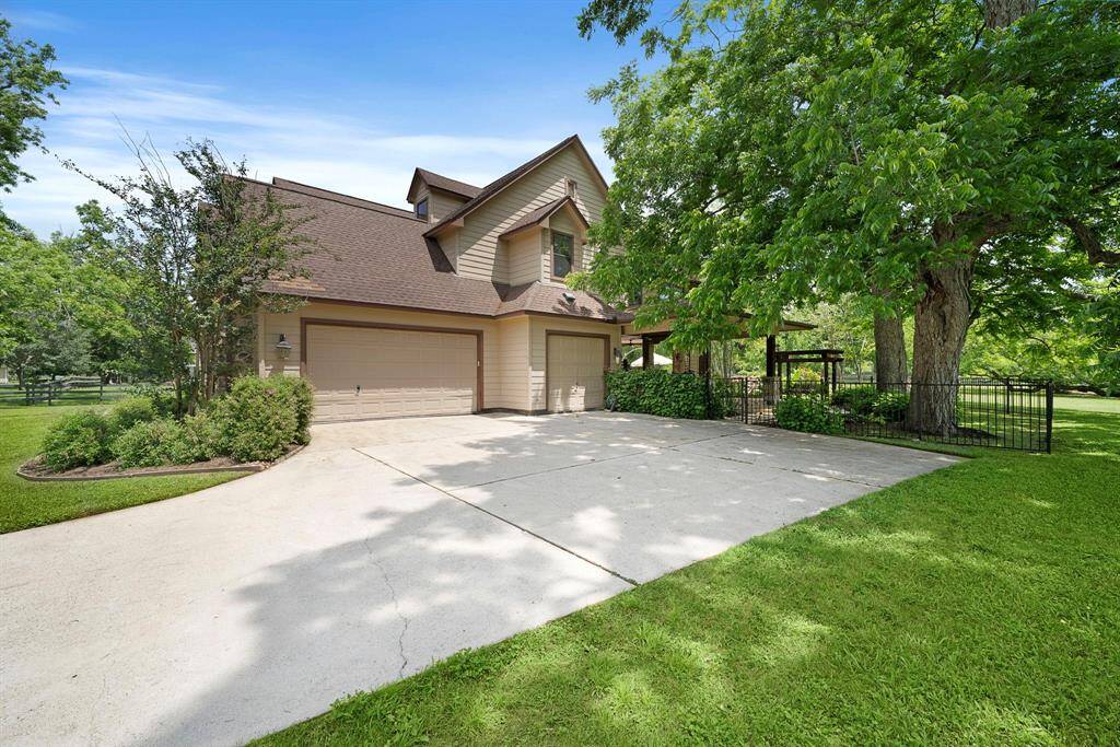 The winding driveway leads to a 3-car garage as well as additional exterior parking for guests.  Here you can see the back patio access through a side gate.