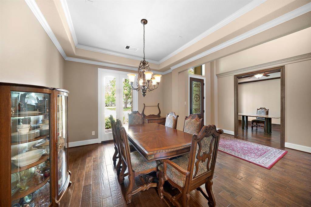 This elegant dining room features hardwood floors, a classic chandelier, and a large window for natural light.