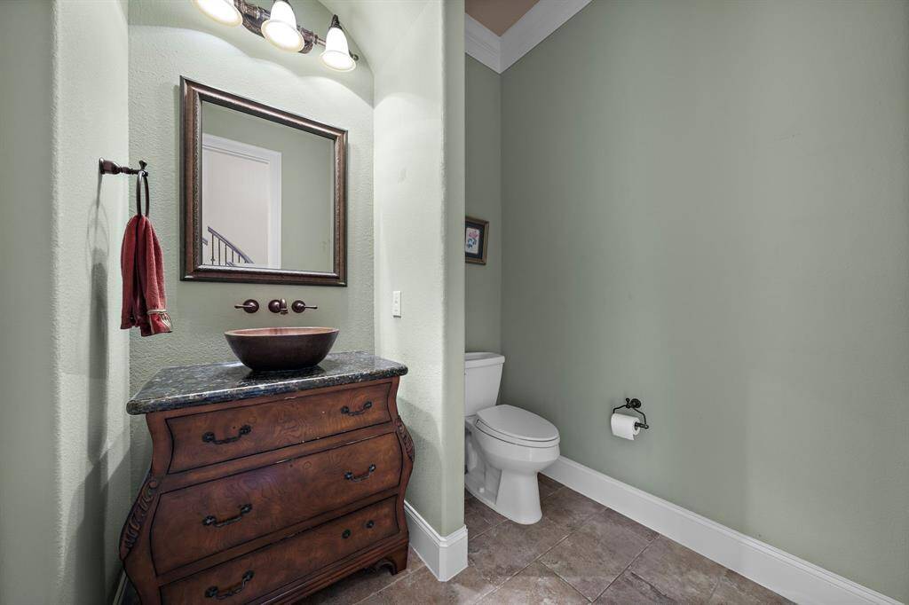 The guest half bathroom has a classic design with soft green walls and a stylish vanity with a vessel sink.