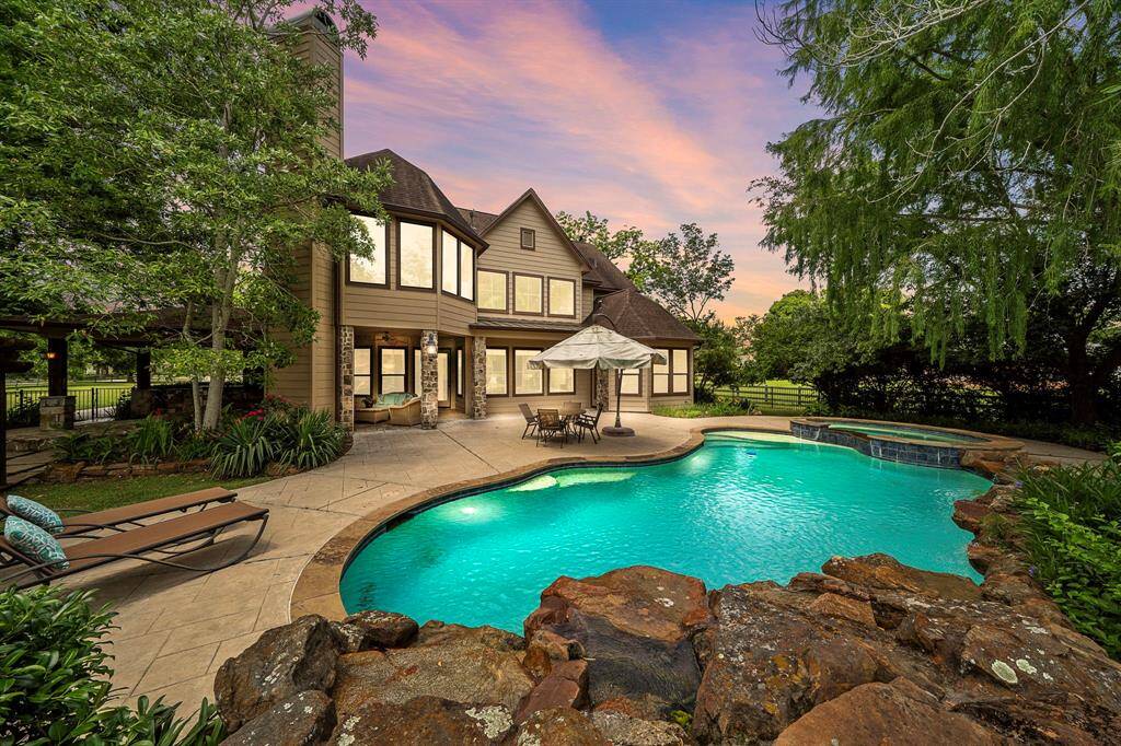 This backyard features a luxurious pool and spa, surrounded by lush greenery and a charming patio area perfect for outdoor gatherings.