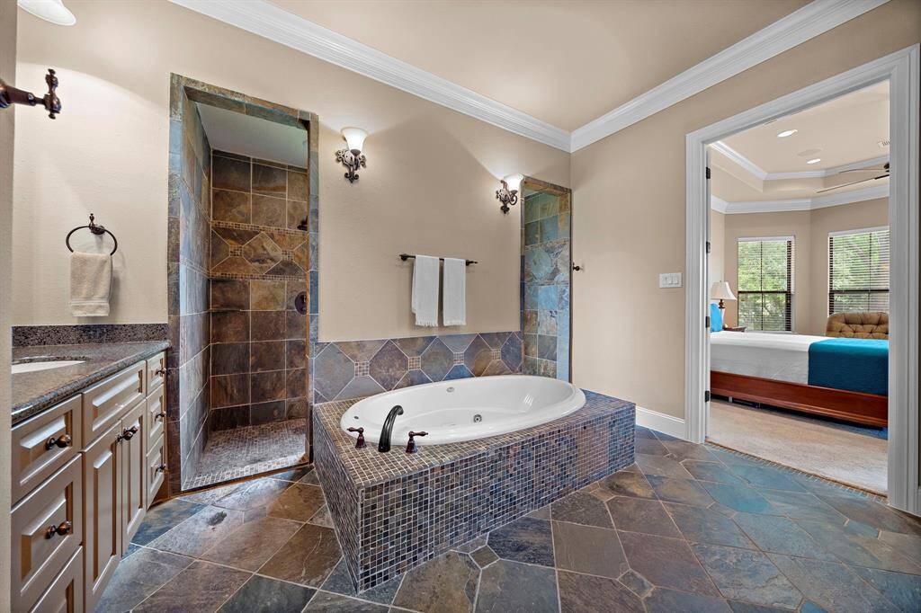 This lovely tiled walk-in shower boasts earthy tones and natural stone patterns. It features dual showerheads and a large, frosted window for privacy and natural light.